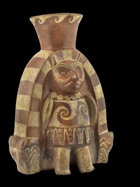 Cántaro escultórico que representa a personaje antropomorfo con cabeza y alas de búho o lechuza. Tiene un collar de cuentas circulares, camisa con diseños de olas o espirales entrelazadas y faldellín. Está parado debajo de un arco formado por una serpiente de dos cabezas felínicas. En el gollete del cántaro hay diseños de olas. Cultura Mochica.