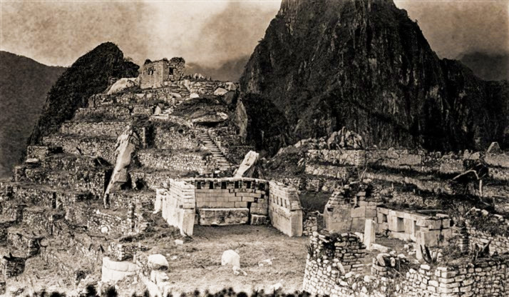 Foto: Hiram Bingham 26 / 40 Vista general de la Plaza Sagrada El emplazamiento de Machu Picchu donde se concentran los edificios que ostentan una mejor calidad arquitectónica. En el centro se yergue el Templo Principal; a la derecha, el templo de las Tres Ventanas. Sobre ambos templos descuella la colina sagrada, en cuya cima aguarda la piedra Intiwatana, o reloj de sol.
